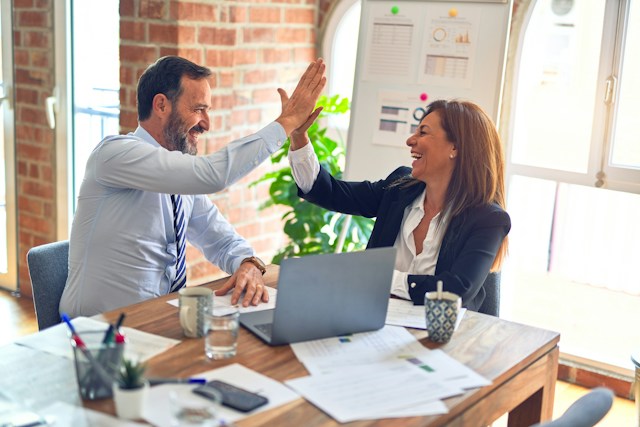 Two people high-fiving at a desk