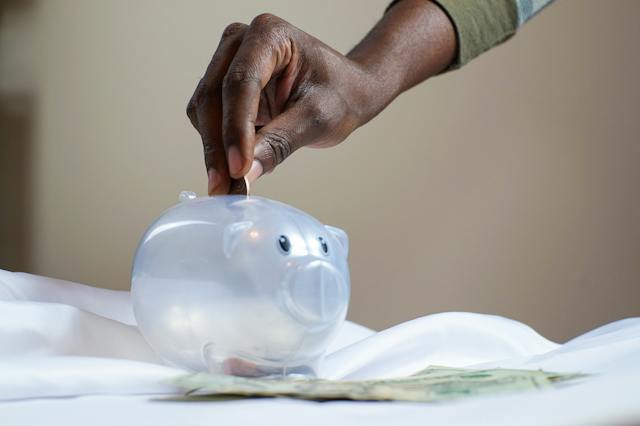 A hand inserting a coin into a piggybank.