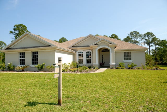A large home with a sign in the lawn.